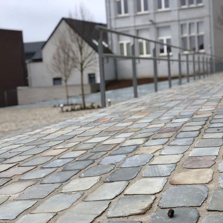 Best close-up image for Reclaimed European Sandstone Cobblestones - Rectangle - Flat Surface. The surface finish shown is sawn. The dominant color shown is gray; with beige, green, orange/rust, purple, white and tan secondaries. Exhibits "movement". Regular color pattern.