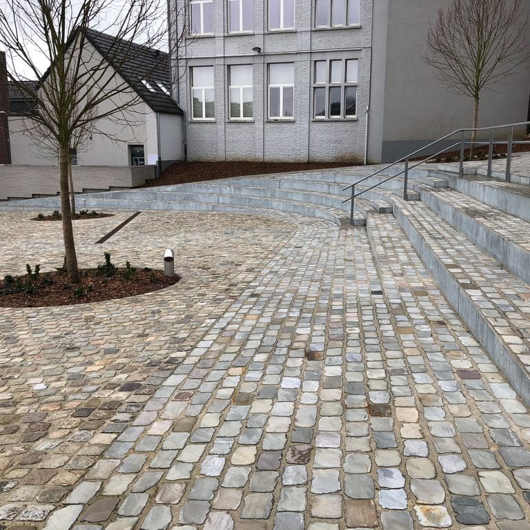 Application image for Sandstone - Reclaimed European Cobblestones - Rectangle - Flat Surface. The image shows this product being used for patio pavers and public area. The surface finish shown is sawn. The dominant color shown is gray. The color mix creates a warm feeling.