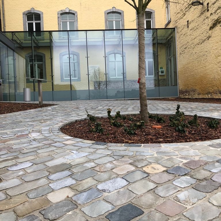 Application image for Sandstone - Reclaimed European Cobblestones - Rectangle - Flat Surface. The image shows this product being used for patio pavers and public area. The surface finish shown is sawn. The dominant color shown is gray.
