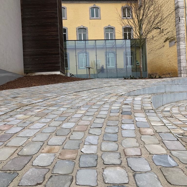 Application image for Sandstone - Reclaimed European Cobblestones - Rectangle - Flat Surface. The image shows this product being used for patio pavers and public area. The surface finish shown is sawn. The dominant color shown is gray.
