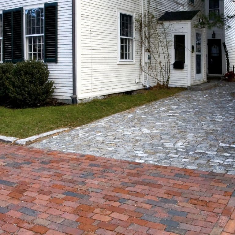 Feature image for Reclaimed Boston Brick Pavers. The image shows this product being used for driveway pavers and driveway aprons. Dominant colors shown are pink and red; with black, purple and tan secondaries. The color mix creates a warm feeling. Regular color pattern.
