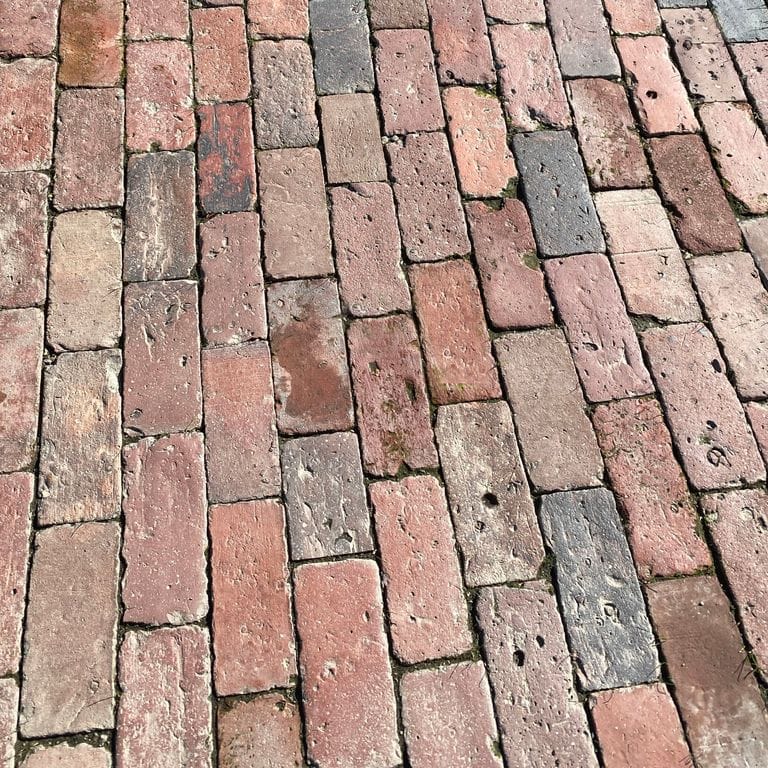 Application image for Reclaimed Boston Brick Pavers. The image shows this product being used for driveway pavers, path pavers, patio pavers and driveway aprons. Dominant colors shown are gray, pink and red. The color mix creates a warm feeling. Regular color pattern.