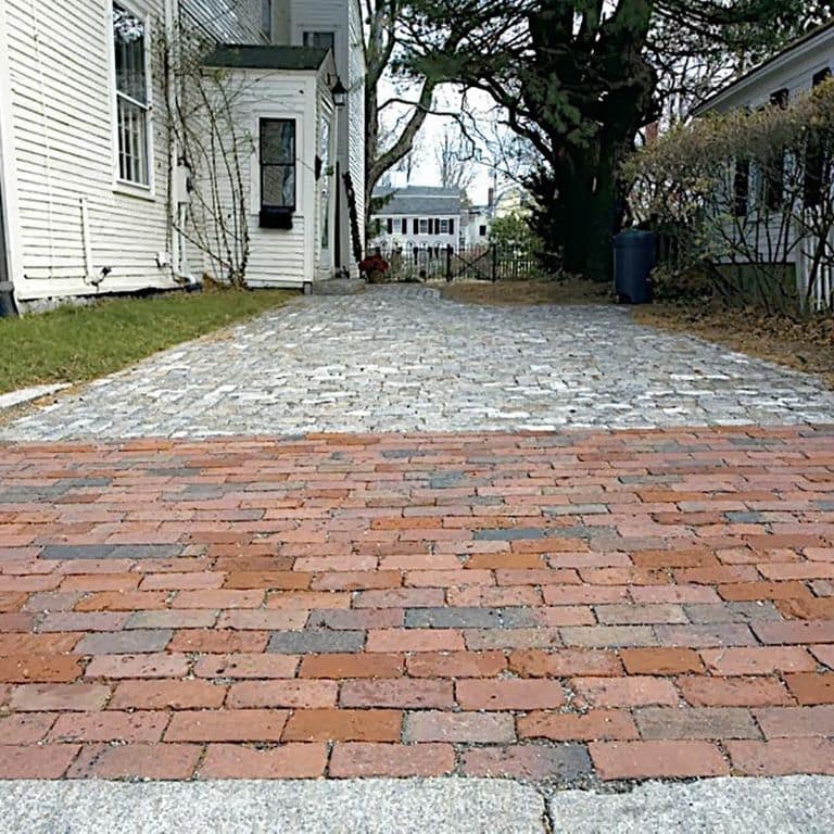 Application image for Brick - Reclaimed Boston Pavers. The image shows this product being used in a driveway aprons application. The surface finish shown is . Dominant colors shown are gray and red. The color mix creates a warm feeling. Regular color pattern.