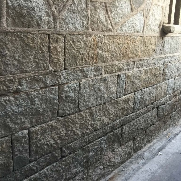 Application image for Reclaimed Granite Plank Veneer. The image shows this product being used in a full bed veneer application. The surface finish shown is . The dominant color shown is gray. The color mix creates a warm feeling. Regular color pattern.