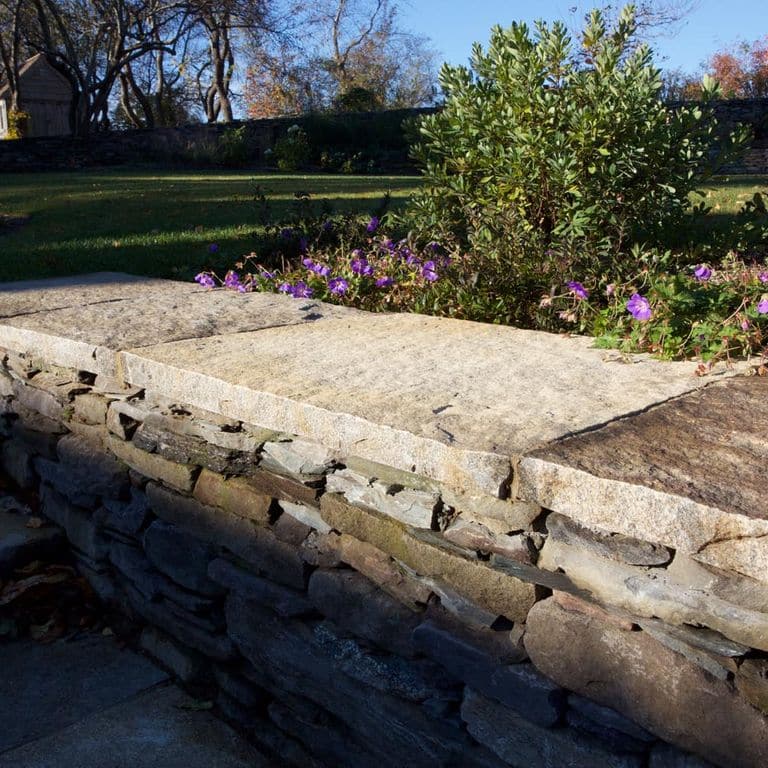 Close-up image for Reclaimed Granite Capstones. Dominant colors shown are beige, brown and tan; with orange/rust and cream secondaries. Exhibits "movement" and the color mix creates a warm feeling. Regular, speckled, fine speckled, blotched and streaked color patterns.