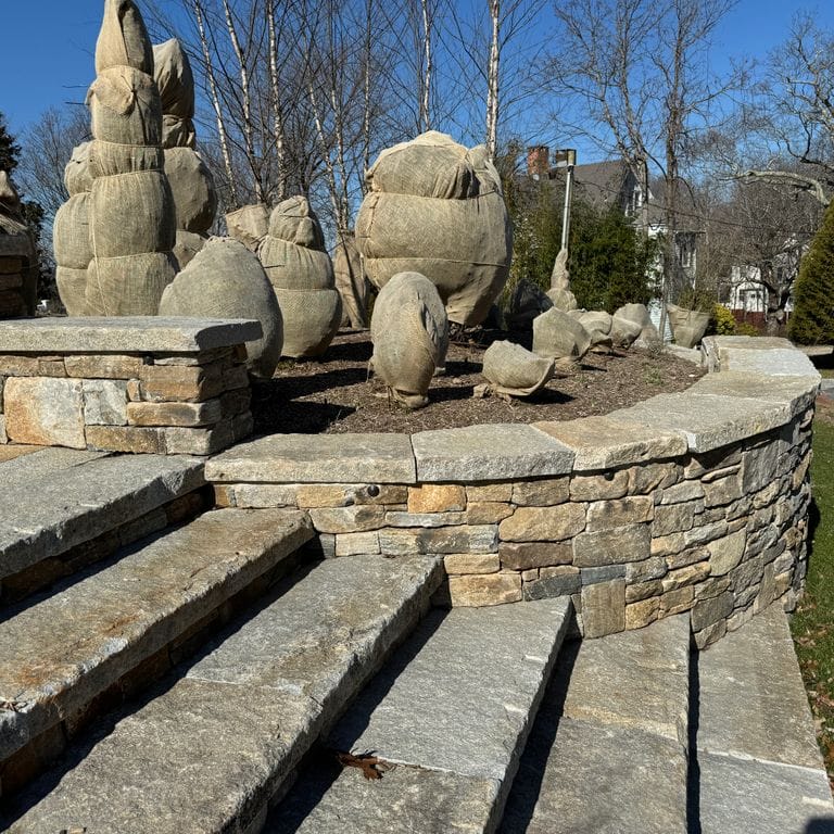 Application image for Reclaimed Granite Capstones. The image shows this product being used in a wallstone cap application. Dominant colors shown are beige and gray.