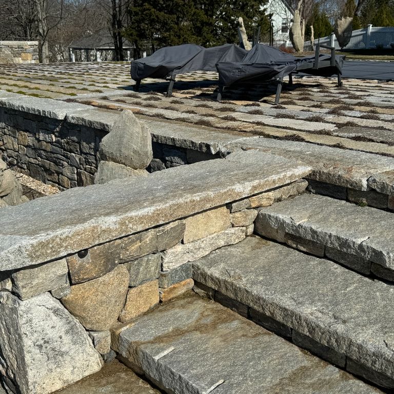 Application image for Reclaimed Granite Capstones. The image shows this product being used in a wallstone cap application. The dominant color shown is gray. The color mix creates a warm feeling.