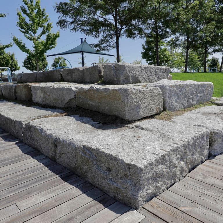 Application image for Reclaimed Granite Bridge Blocks - Benches and Seating. The image shows this product being used in a seating &amp; benches application. This is a landscape stone for outdoor commercial and residential applications. Suitable for general use, freeze-thaw conditions, low heat absorption surfaces and low slipperiness surfaces situations. Relatively higher in price.