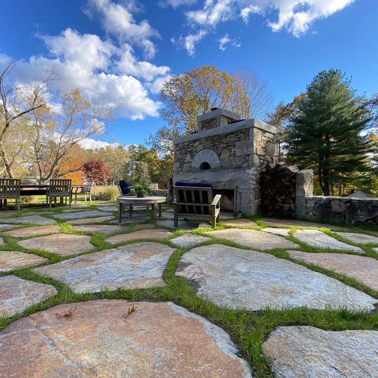 Feature image for Goshen Stone - Irregular Flagstone. The image shows this product being used in a patio pavers application. Dominant colors shown are brown, gray and tan; with beige, orange/rust, purple, white and cream secondaries. Exhibits "movement" and the color mix creates a warm feeling. Speckled, blotched, random and cloudy color patterns. Contains lots of mica and mineral inclusions.