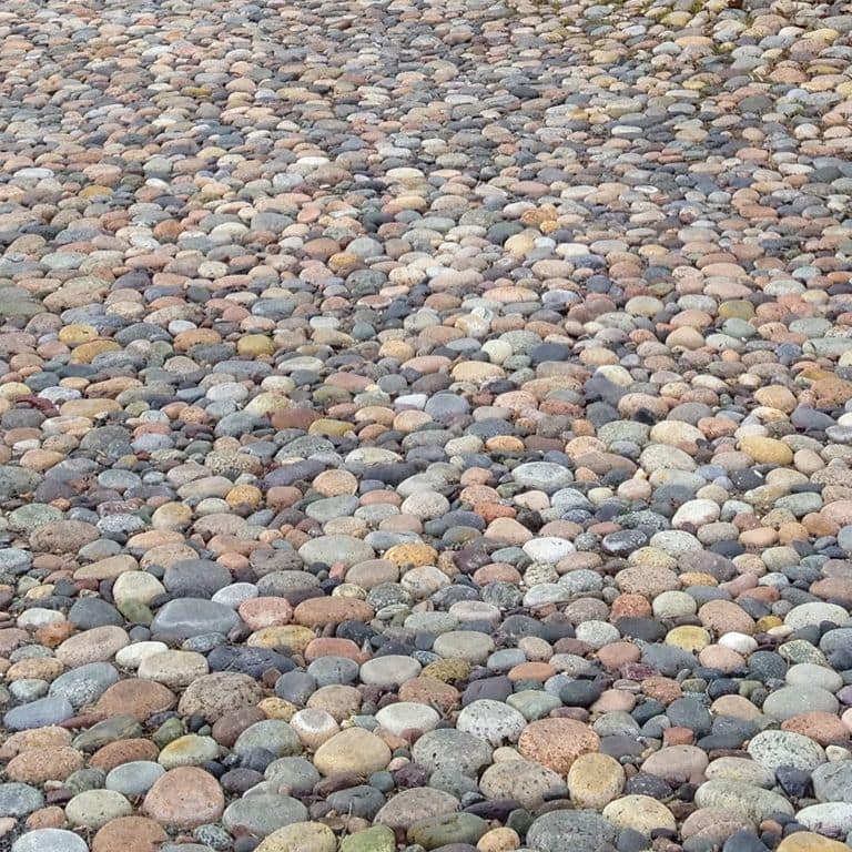 Close-up image for Beach Rounds Pavers. The surface finishes shown are natural and worn. The dominant color shown is gray; with beige, black, blue, brown, green, orange/rust, pink, purple, white, tan and cream secondaries. Exhibits "movement" and the color mix creates a warm feeling. Random, speckled, coarse speckled and cloudy color patterns.