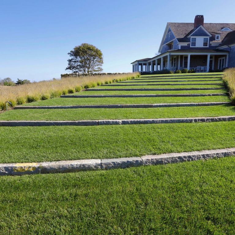 Feature image for Reclaimed First Generation Granite Curbstone - Lawn Steps. The image shows this product being used for landscape curbing &amp; edging and monolithic steps. The surface finish shown is . The dominant color shown is gray; with brown and tan secondaries. The color mix creates a cool feeling. Speckled color pattern.
