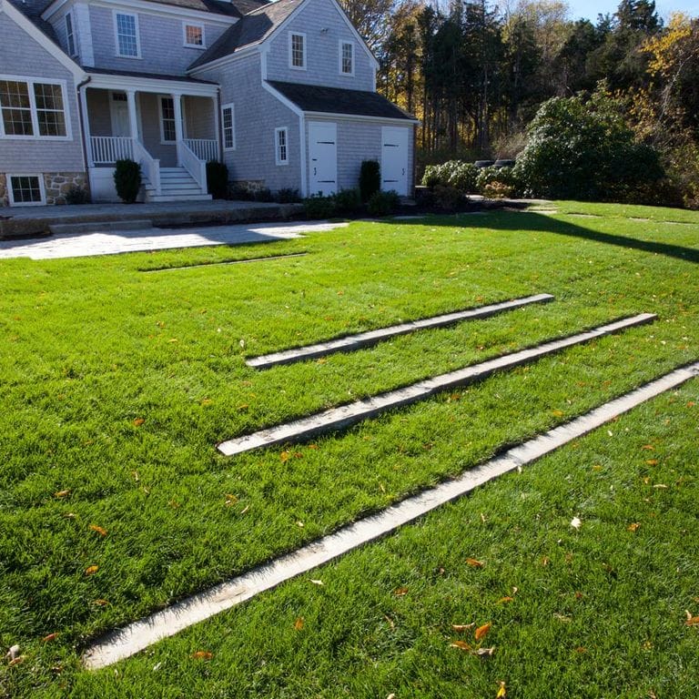 Application image for Reclaimed First Generation Granite Curbstone - Lawn Steps. The image shows this product being used in a monolithic steps application. The surface finish shown is a combination of weathered and worn. The dominant color shown is gray; with a tan secondary. The color mix creates a cool feeling. Regular color pattern.