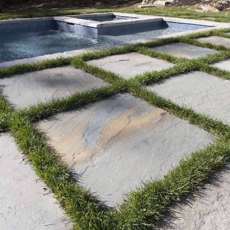 Application image for Bluestone - Full Color Mix Dimensional Cut Pavers Natural Cleft. The image shows this product being used in a pool deck pavers application. The surface finish shown is natural cleft. The dominant color shown is gray. The color mix creates a warm feeling.