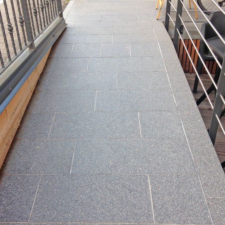 Feature image for Porphyry Worked Surface - Gray Real Dimensional Pavers. The image shows this product being used in a path pavers application. The dominant color shown is gray. The color mix creates a cool feeling. Speckled color pattern.