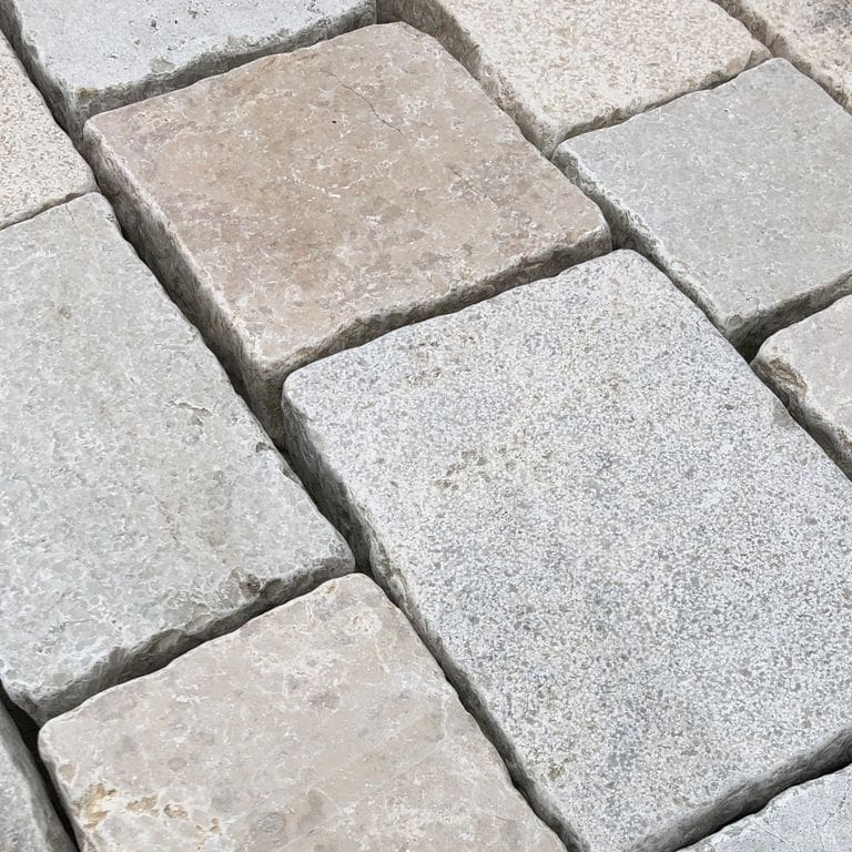 Best close-up image for Limestone - Mountain Hard - Cobblestones Mix. The surface finish shown is a combination of flamed and sand blasted. Dominant colors shown are beige, gray and white; with pink and cream secondaries. Regular, speckled, blotched and cloudy color patterns.