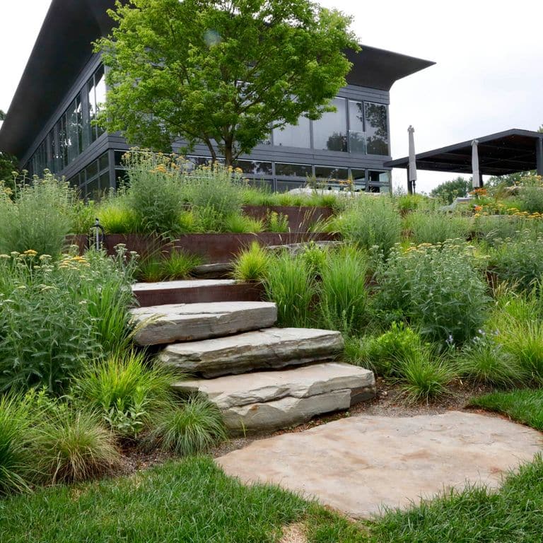 Feature image for Mystic Mountain Natural - Steps &amp; Landings. The image shows this product being used for landings and monolithic steps. Dominant colors shown are beige and gray; with brown, orange/rust, white and tan secondaries. Exhibits "movement". Blotched and cloudy color patterns.