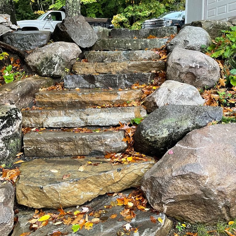 Application image for Mystic Mountain Natural - Steps &amp; Landings. The image shows this product being used in a monolithic steps application. The surface finish shown is natural cleft. Dominant colors shown are brown and gray; with orange/rust, white and tan secondaries. The color mix creates a warm feeling.