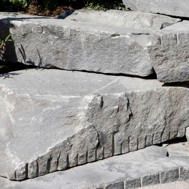 Close-up image for Reclaimed New England Granite Quarry Tailings - Seating. The dominant color shown is gray; with beige, purple and white secondaries. Exhibits "movement" and the color mix creates a cool feeling. Regular, blotched, swirled and cloudy color patterns.