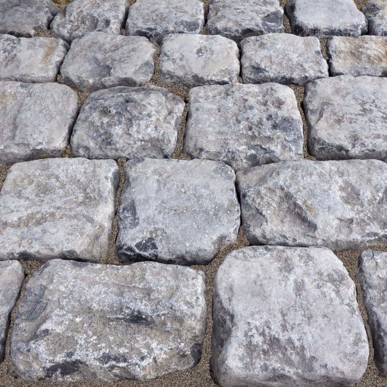 Best close-up image for Reclaimed Belgian Bluestone Cobblestones - Worn Surface. The image shows this product being used in a driveway pavers application. The surface finish shown is . The dominant color shown is gray; with blue, brown and white secondaries. Blotched and random color patterns.
