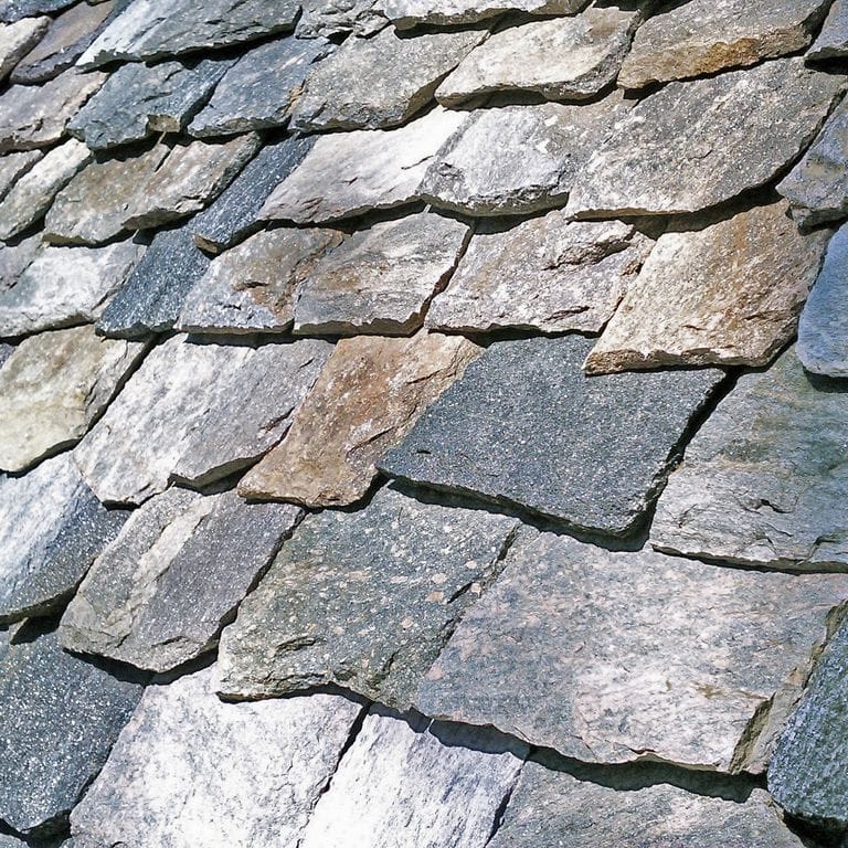 Close-up image for New England Granite Mix - Roof Shingles. The surface finish shown is split-face. The dominant color shown is gray; with beige, blue, brown, green, purple and white secondaries. Exhibits "movement". Random color pattern.