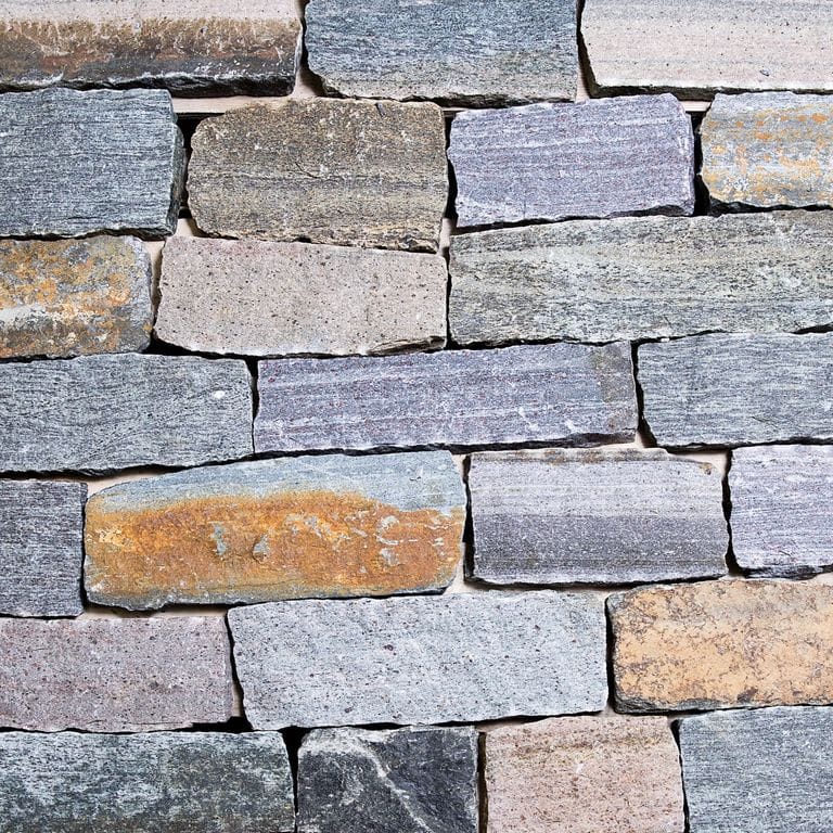Color/Finish variation image for Adirondack Granite - Veneer. The surface finish shown is split-face. Dominant colors shown are blue, gray and greige. The color mix creates a warm feeling.