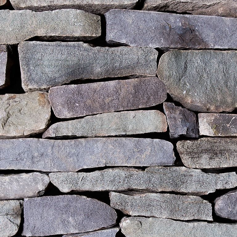 Color/Finish variation image for Old Yankee Fieldstone - Veneer. The image shows this product being used for full bed veneer and thin veneer. The surface finish shown is split-face. The dominant color shown is gray; with beige, blue, brown, orange/rust, pink, purple, white and tan secondaries. Exhibits "movement". Speckled, blotched and cloudy color patterns.