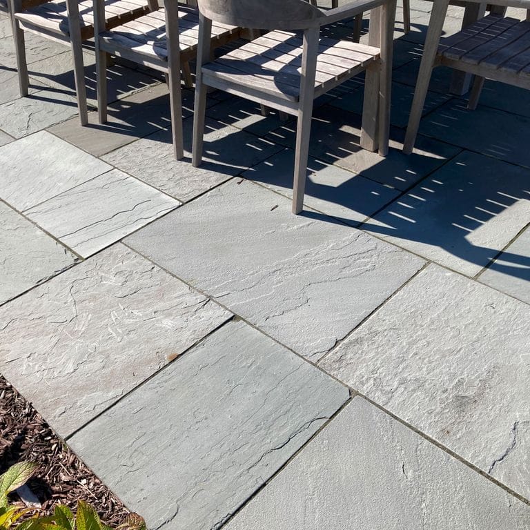 Feature image for Bluestone Natural Cleft Blue/Gray - Dimensional Cut Pavers. The image shows this product being used in a patio pavers application. The surface finish shown is natural cleft. Dominant colors shown are blue and gray. The color mix creates a cool feeling. Solid and regular color patterns.