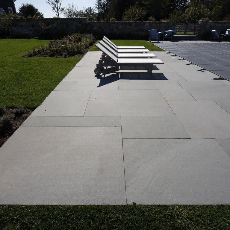 Application image for Bluestone Flamed Surface Blue/Gray - Dimensional Cut Pavers. The image shows this product being used in a pool deck pavers application. The surface finish shown is flamed. The dominant color shown is gray; with a blue secondary. The color mix creates a cool feeling. Solid color pattern.