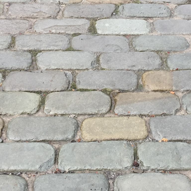 Close-up image for Bluestone Full Color - Cobblestone Pavers. The surface finishes shown are flamed and tumbled. The dominant color shown is gray; with beige, pink, purple, white and tan secondaries. The color mix creates a warm feeling. Regular color pattern.