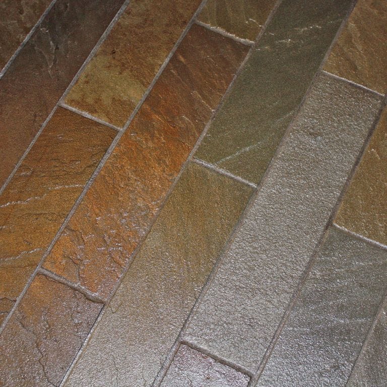 Close-up image for Bluestone Natural Cleft Burgundy/Brown - Interior Flooring. The surface finish shown is natural cleft. The dominant color shown is brown; with green, gray, orange/rust and purple secondaries. Exhibits "movement" and the color mix creates a warm feeling. Random color pattern.