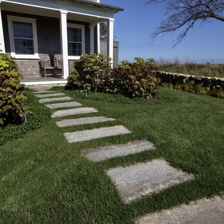 Feature image for Reclaimed First Generation Curbstone - Steppers. The image shows this product being used in a path pavers application. The surface finish shown is . The dominant color shown is gray. The color mix creates a cool feeling.