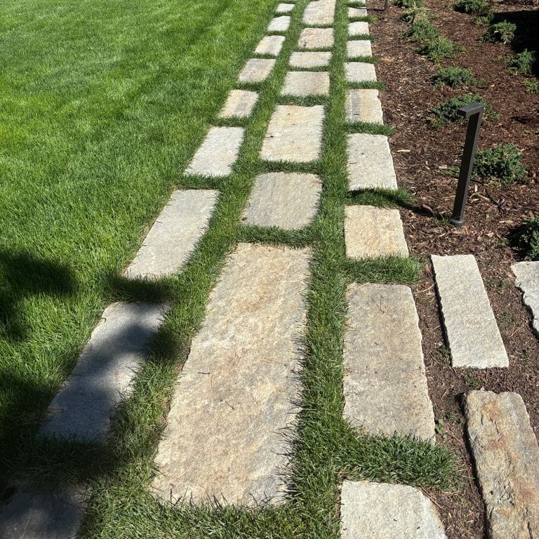 Application image for Reclaimed First Generation Curbstone - Steppers. The image shows this product being used in a patio pavers application. The surface finish shown is . The dominant color shown is gray. The color mix creates a warm feeling.