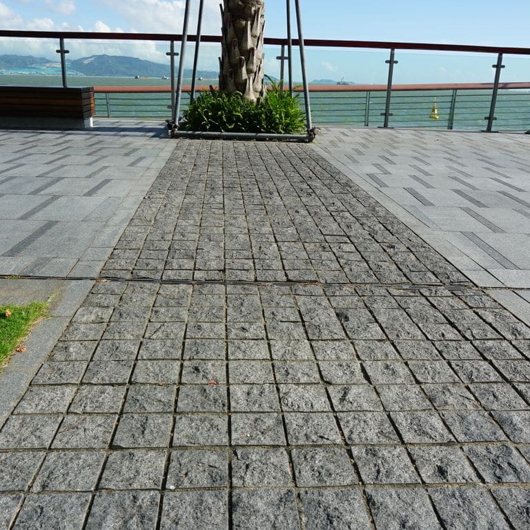 Feature image for Basalt - Ankar Gray - Cobblestones. The image shows this product being used in a public area application. The dominant color shown is gray. Exhibits "movement". Regular, speckled and blotched color patterns.