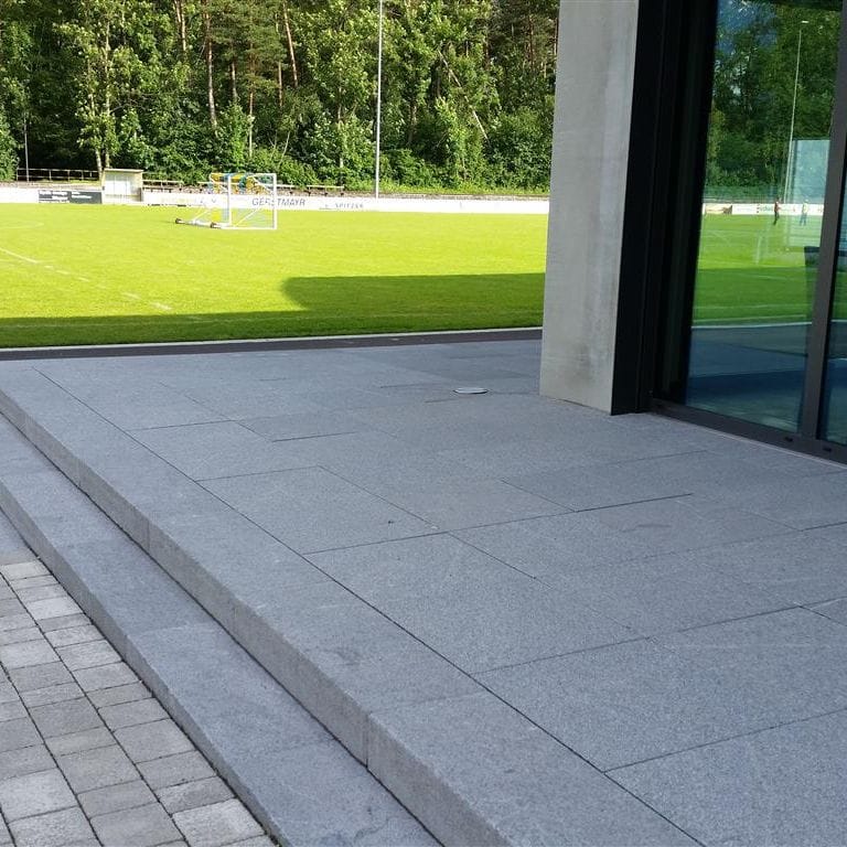 Feature image for Granite- Republic Black - Treads. The image shows this product being used for landings and treads. Dominant colors shown are blue and gray. The color mix creates a cool feeling. Speckled and cloudy color patterns.