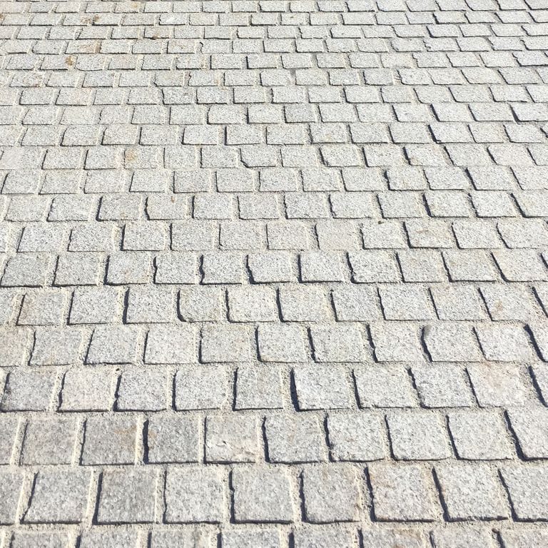 Close-up image for Gray Ariz Granite - Cobblestones. The surface finish shown is split-face with flat plane. The dominant color shown is gray; with beige, white and cream secondaries. The color mix creates a cool feeling. Regular and speckled color patterns. Contains some mica and mineral inclusions.
