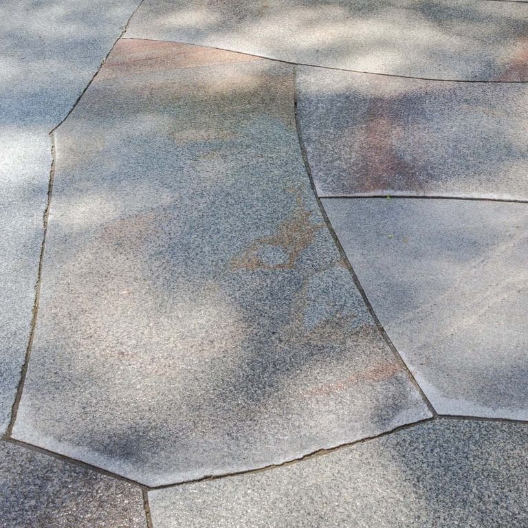 Close-up image for Cape Neddick Granite Full Color - Cut to Fit Pavers. The surface finish shown is flamed. The dominant color shown is gray; with beige, blue, orange/rust, purple and white secondaries. Exhibits "movement" and the color mix creates a cool feeling. Speckled, blotched and veined color patterns.