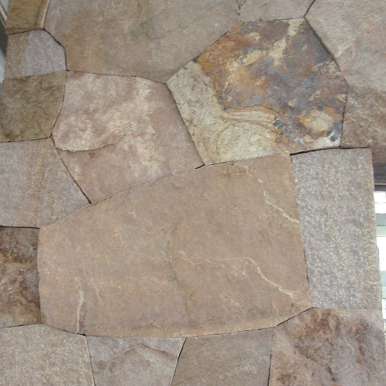 Close-up image for Quarried Chinese Granite - Quarry Skin Veneer. The surface finish shown is split-face with flat plane. Dominant colors shown are brown, gray, orange/rust and tan; with beige and purple secondaries. Exhibits "movement". Random, speckled, blotched and swirled color patterns.