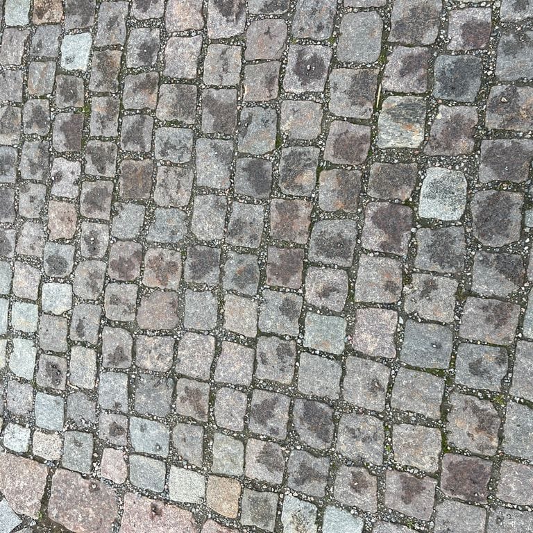 Application image for Reclaimed European Porphyry Cobblestones - Worn Cubes. The image shows this product being used for path pavers, patio pavers and public area. The surface finish shown is . The dominant color shown is gray. The color mix creates a warm feeling.