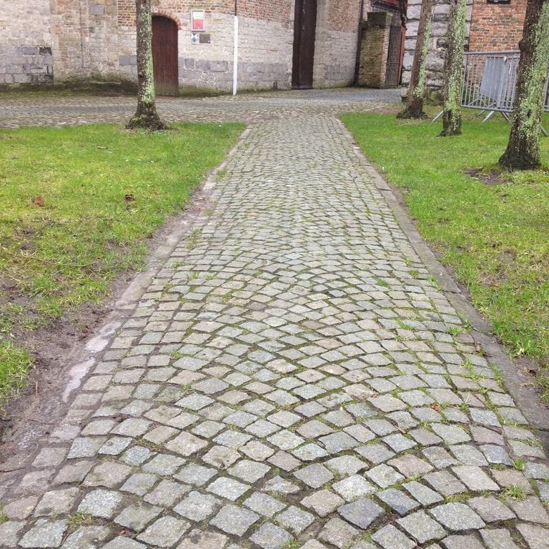Application image for Reclaimed European Porphyry Cobblestones - Worn Cubes. The image shows this product being used in a path pavers application. The surface finish shown is . The dominant color shown is gray. The color mix creates a warm feeling.