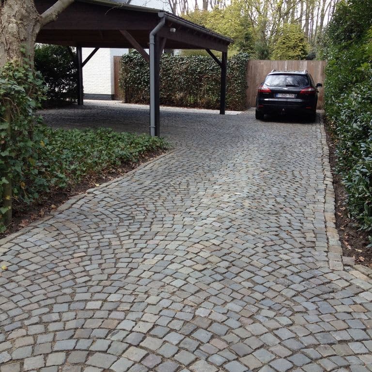 Application image for Reclaimed European Sandstone Cobblestones - Worn Cubes. The image shows this product being used in a driveway pavers application. The surface finish shown is . The dominant color shown is gray. The color mix creates a warm feeling.