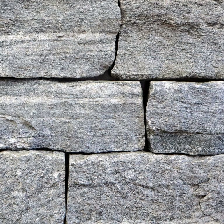 Best close-up image for Granite - Chester Veneer - End Grain Splitface. The image shows this product being used in a thin veneer application. The surface finish shown is split-face. The dominant color shown is gray. The color mix creates a cool feeling. Linear and random color patterns.