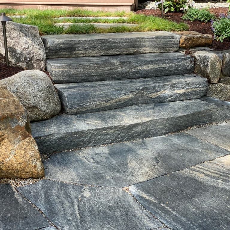 Feature image for Liberty Hill Granite - Monolithic Steps. The image shows this product being used in a monolithic steps application. The dominant color shown is gray; with beige, black, blue, brown, green, purple, white and tan secondaries. Exhibits "movement". Random, blotched and streaked color patterns.