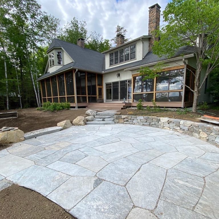 Feature image for Granite- Liberty Hill - Veneer. The image shows this product being used in a patio pavers application. The dominant color shown is gray; with blue, pink, white and tan secondaries. Exhibits "movement" and the color mix creates a cool feeling. Streaked, speckled, blotched and random color patterns.