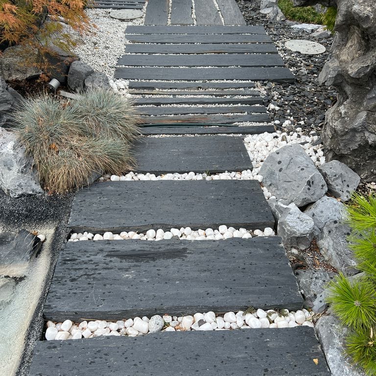 Application image for Black Schist - Pavers. The image shows this product being used in a path pavers application. The surface finish shown is natural cleft. Dominant colors shown are black and gray. The color mix creates a warm feeling.