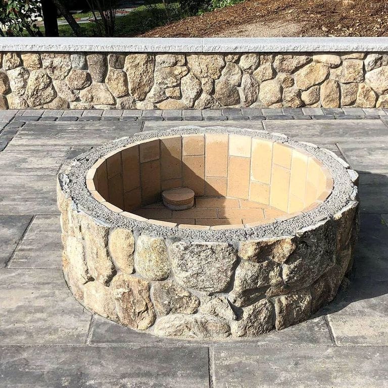 Application image for Fieldstone - Old New England Rounds - Thin Veneer. The image shows this product being used for outdoor fire concepts, landscape wallstone and thin veneer. The surface finish shown is natural. Dominant colors shown are gray and tan. The color mix creates a warm feeling. Speckled and blotched color patterns.