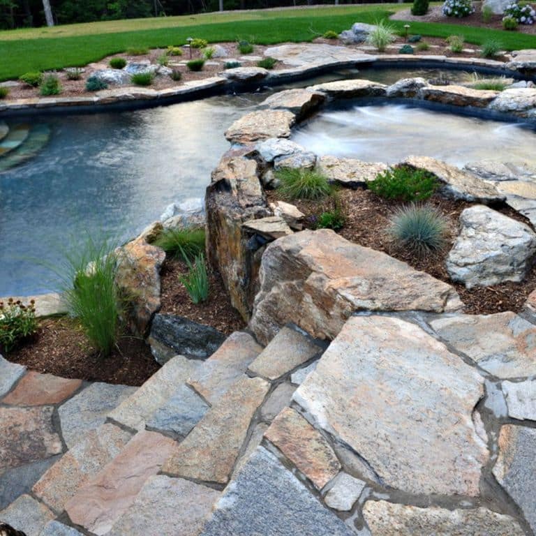 Feature image for Granite- Colonial Tan - Pavers. The image shows this product being used for path pavers and patio pavers. The dominant color shown is gray; with beige, blue, brown, orange/rust, pink, purple and white secondaries. Exhibits "movement". Streaked, speckled, blotched and random color patterns.