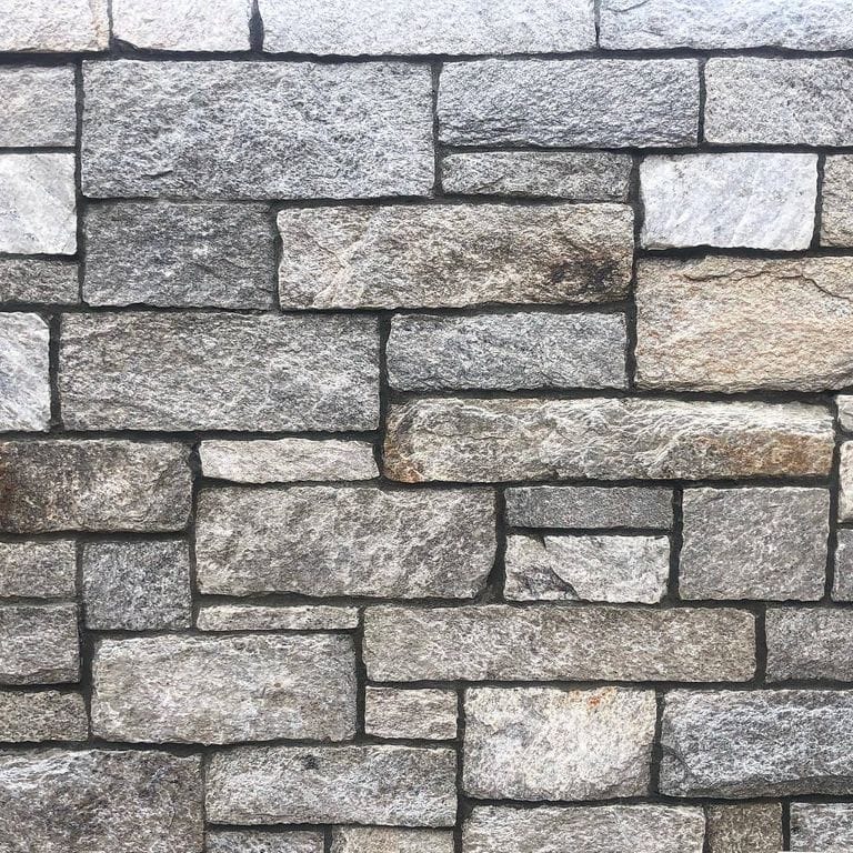 Close-up image for Harbor Mist Granite - Veneer. The surface finish shown is natural. The dominant color shown is gray; with beige, brown, purple, white and cream secondaries. Exhibits "movement" and the color mix creates a cool feeling. Speckled, blotched and cloudy color patterns.