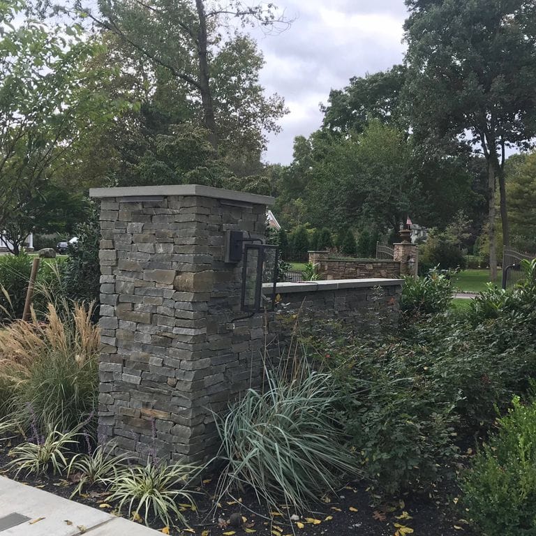 Application image for Colonial Wall Granite - Veneer. The image shows this product being used for full bed veneer and thin veneer. The surface finish shown is split-face with flat plane. The dominant color shown is gray; with black, brown and purple secondaries. Regular color pattern.