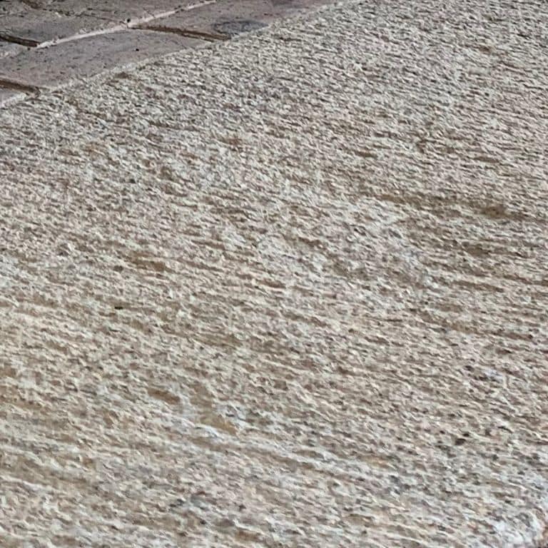 Close-up image for Reclaimed Granite Bridge Blocks - Fireplace Hearth. The surface finishes shown are split-face, weathered and worn. The dominant color shown is gray; with beige and white secondaries. The color mix creates a cool feeling. Speckled color pattern. Contains some mica and mineral inclusions.