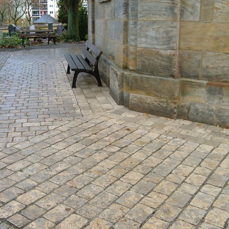 Feature image for Limestone - Bavarian Dolomite - Gray - Cobblestones. The image shows this product being used for path pavers and public area. Dominant colors shown are gray and tan; with beige, brown, green and orange/rust secondaries. Exhibits "movement" and the color mix creates a warm feeling. Random and cloudy color patterns. Contains mineral inclusions.